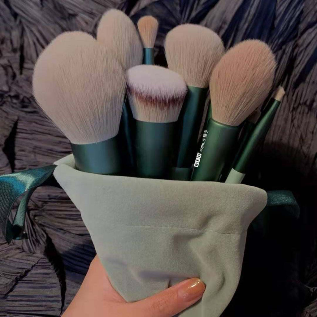 Set of makeup brushes in a green holder held by a hand against a textured background