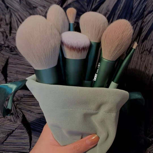 Set of makeup brushes in a green holder held by a hand against a textured background