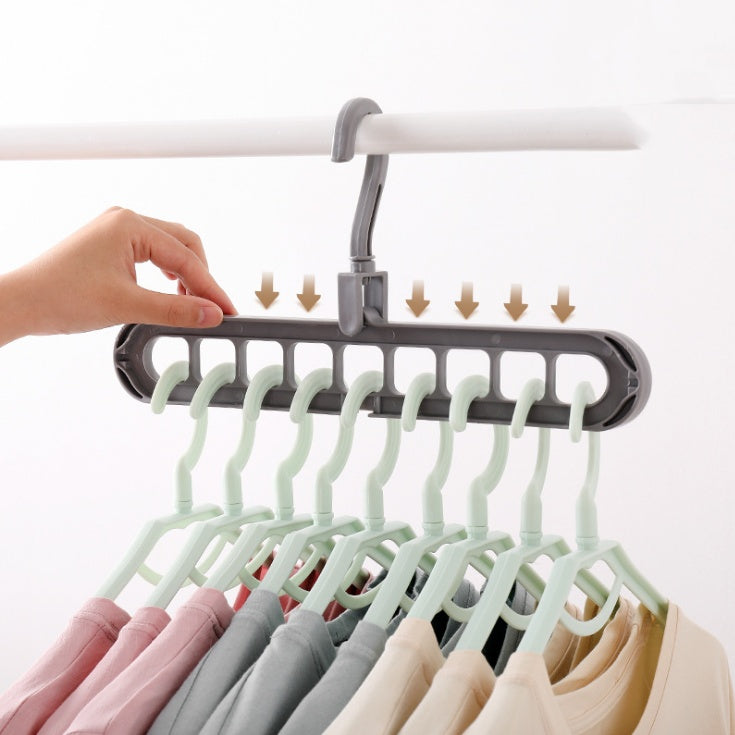  Hand holding grey 9-slot 360 rotating plastic clothes hanger storage hook with hangers loaded